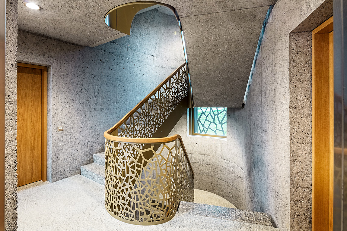 Main staircase made of sandblasted exposed concrete, polished concrete floor, prefabricated staircase elements and perforated steel railing. Photo: PREFA / Croce & Wir | TOWNSET – empathy as a benchmark